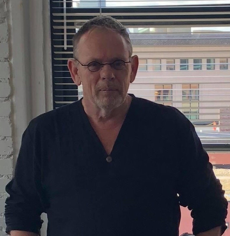 Photo of Brian Flynn standing in a GBLS office wearing a long sleeved black shirt