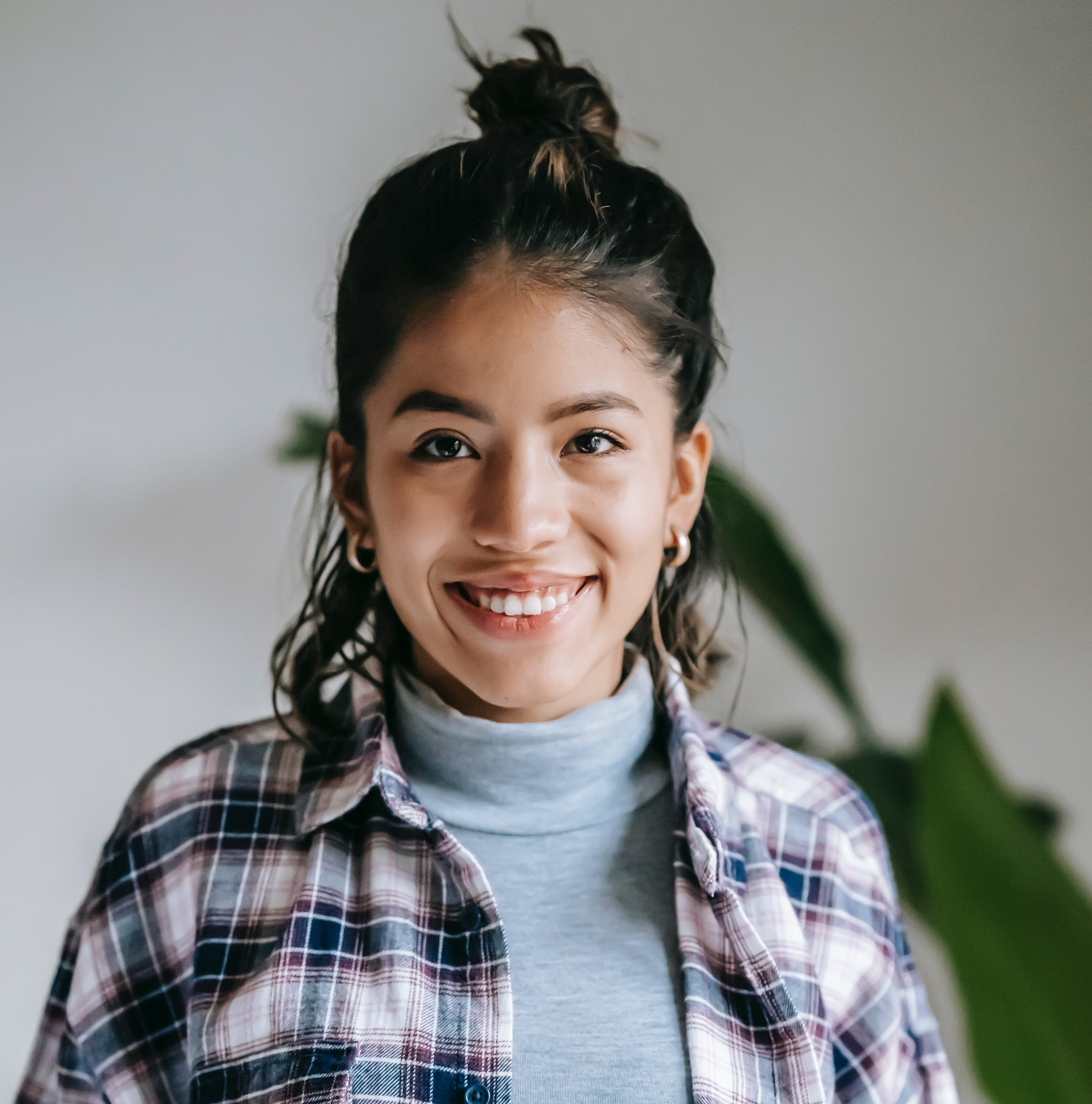 Photo of a woman smiling. She is wearing a turtleneck sweater and flannel shirt.