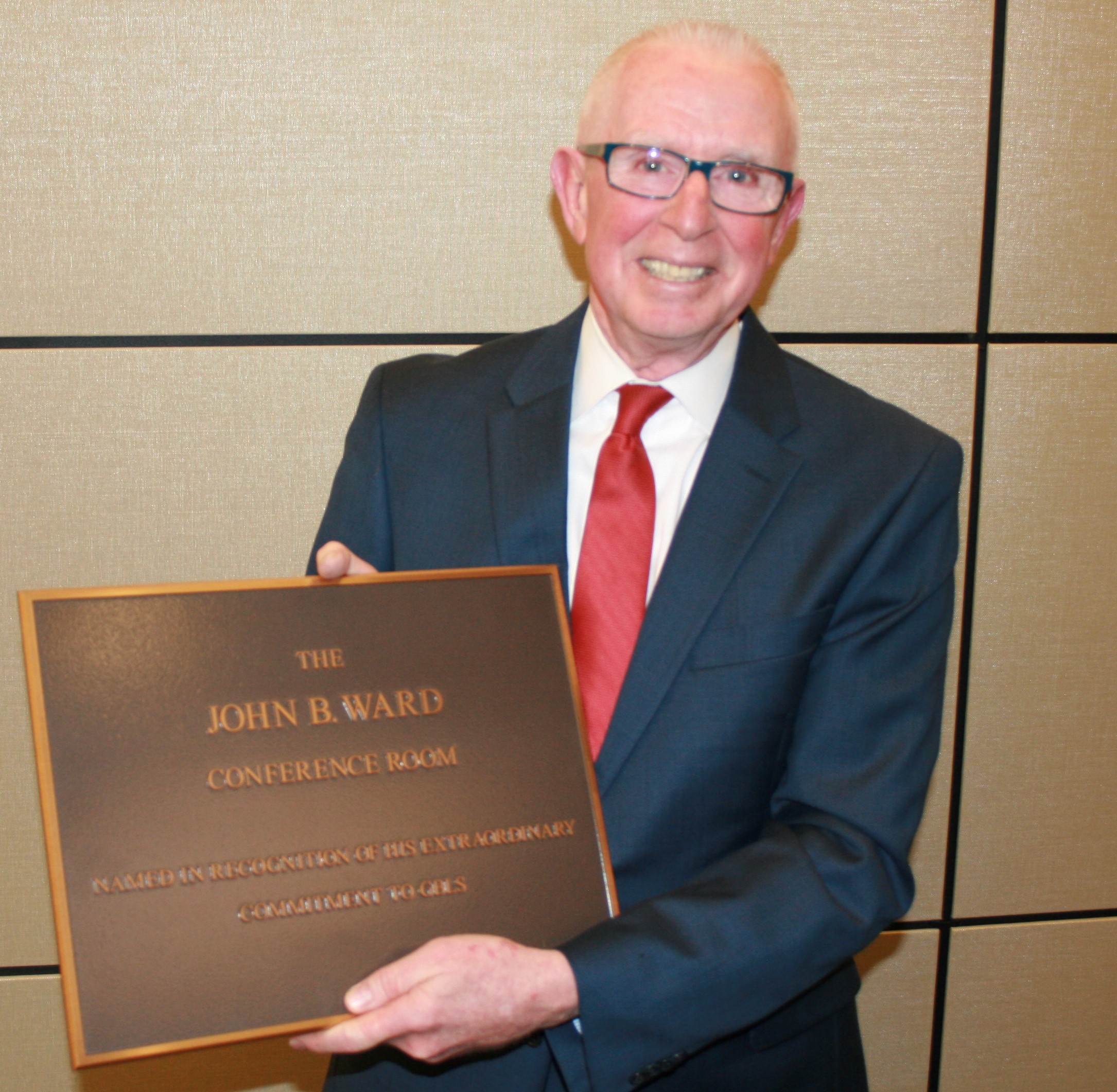 Jack holding a plaque naming a conference room after him