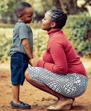 A young boy is standing on the left, while his mother crouches to talk to him eye to eye.