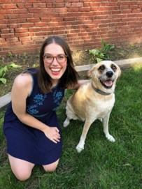 picture of amanda kneeling on the ground next to her dog and smiling