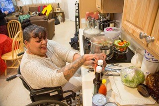 Woman in wheelchair is able to cook in her new accessible apartment