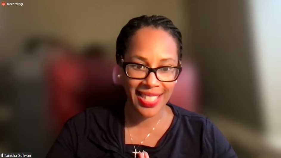Photo of Tanisha Sullivan, who is wearing a black blouse, black glasses, and red lipstick