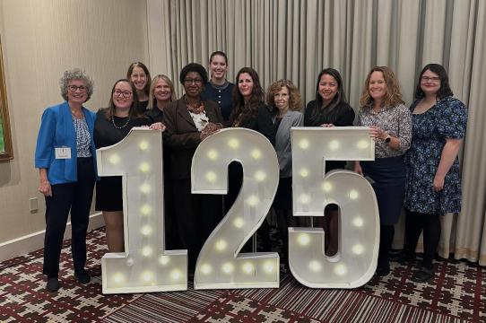 GBLS team standing in front of large lighted numbers 125